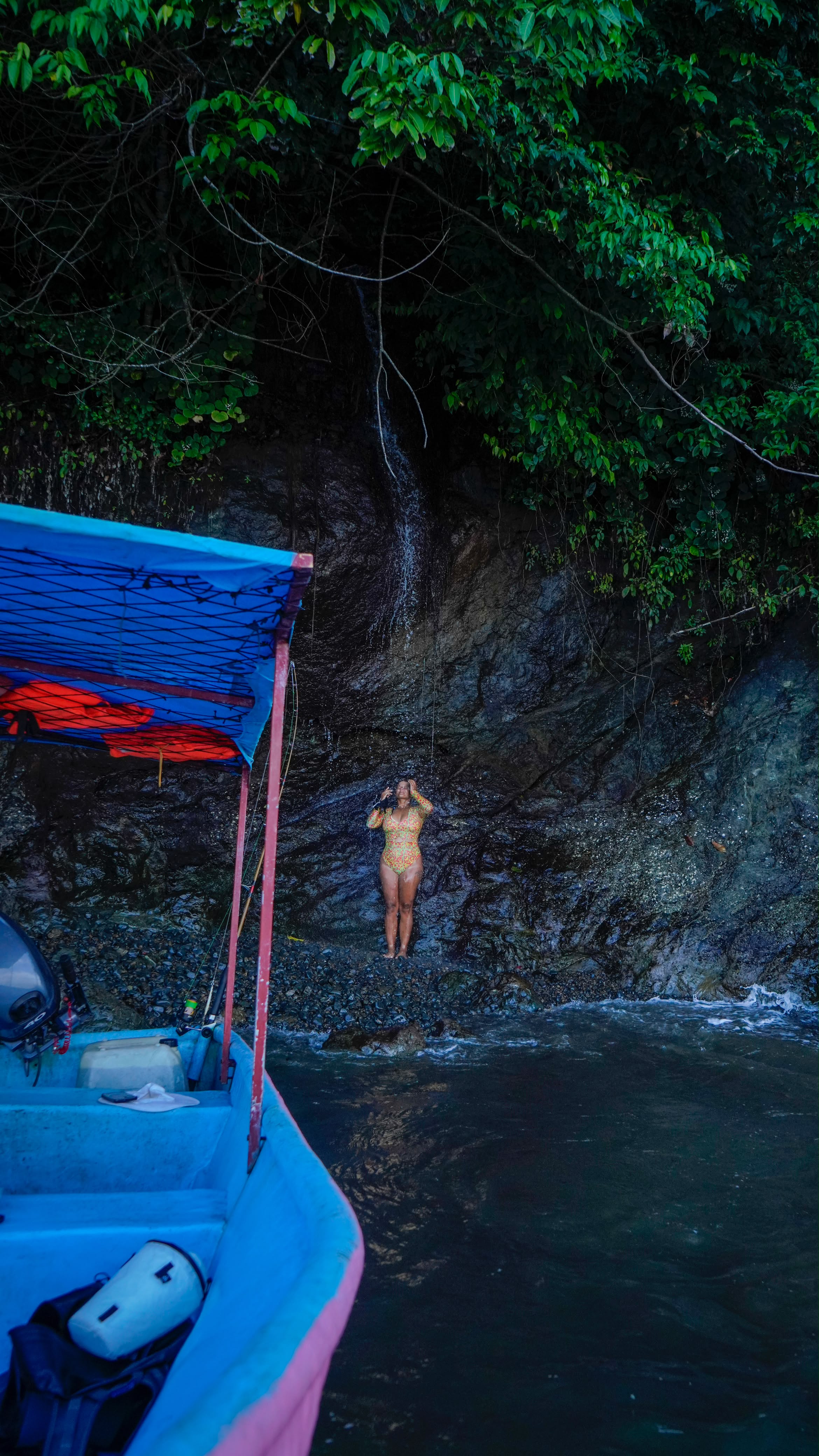 A swimmer under a coastal waterfall on the jungle cliffs of Golfo Dulce