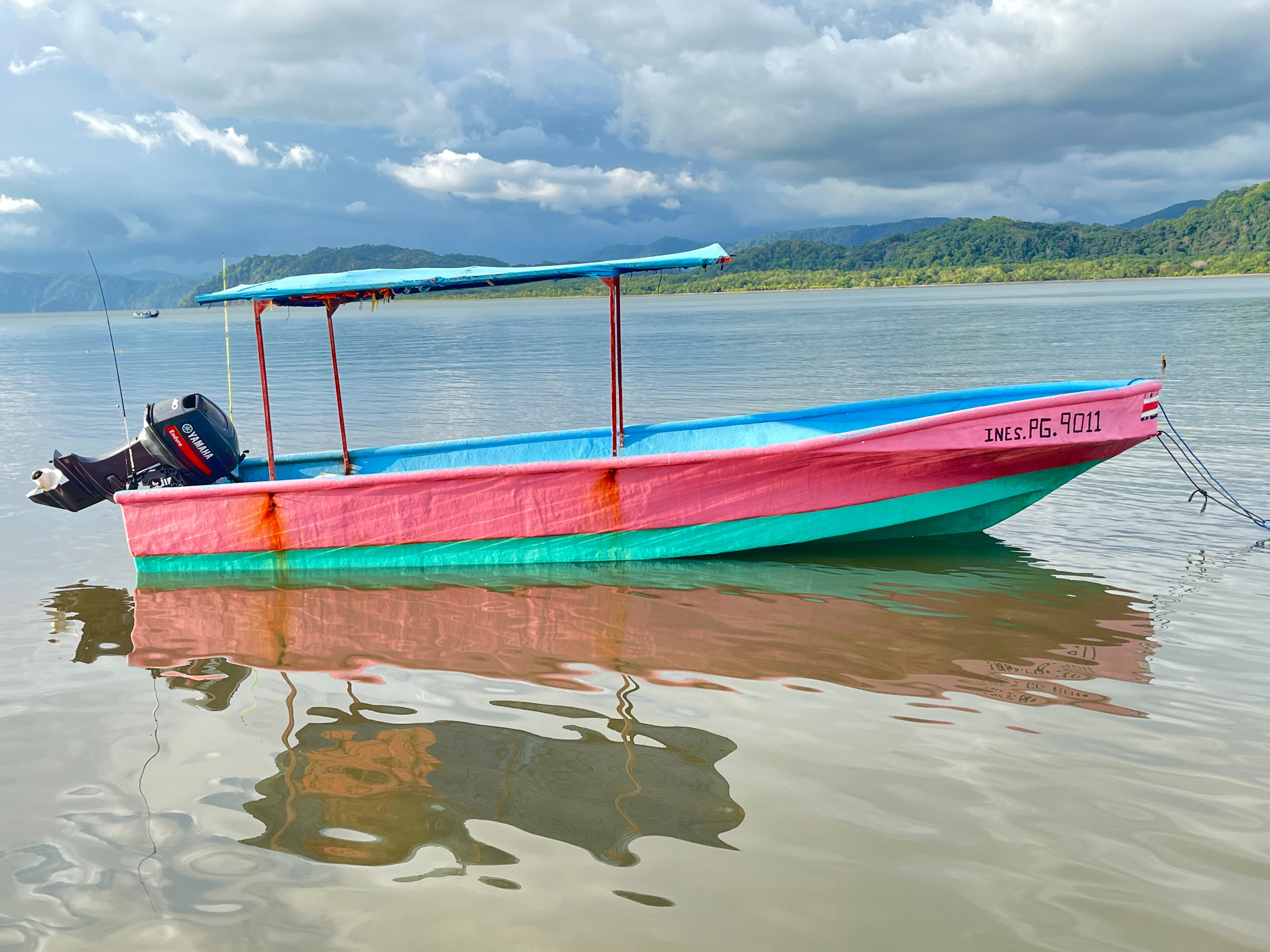A pink and turquoise panga moored in calm water in Pavones, Costa Rica