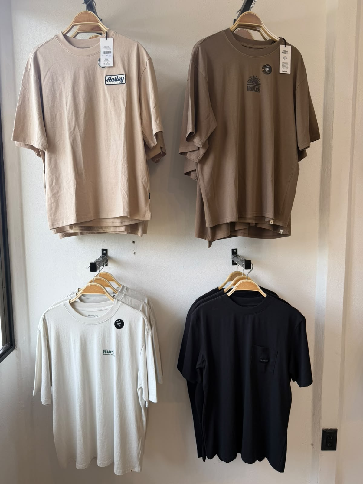 Hurley t-shirts in sand, brown, white and black hanging on the shop wall