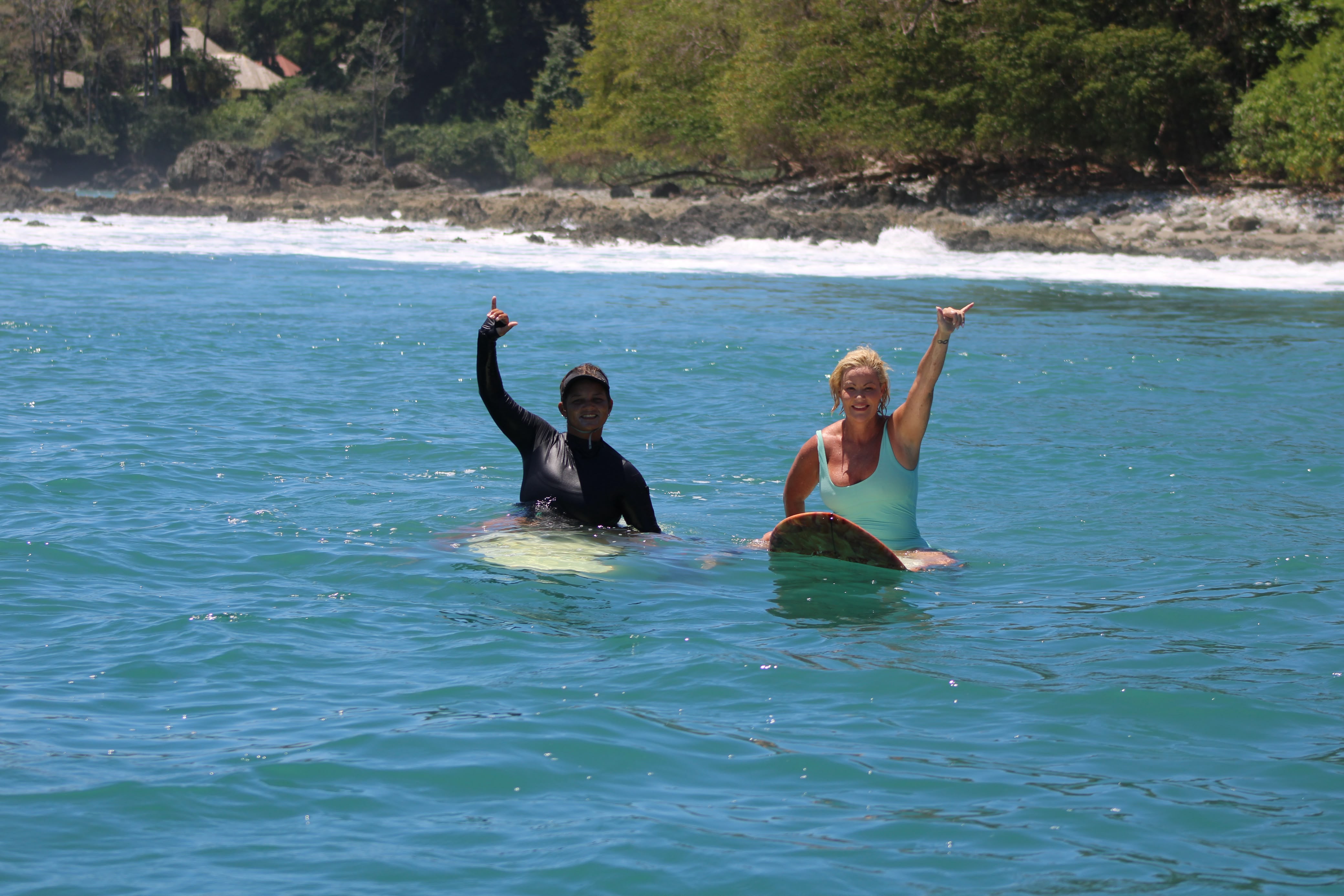 Two surfers throwing shakas in the lineup at a Matapalo point break
