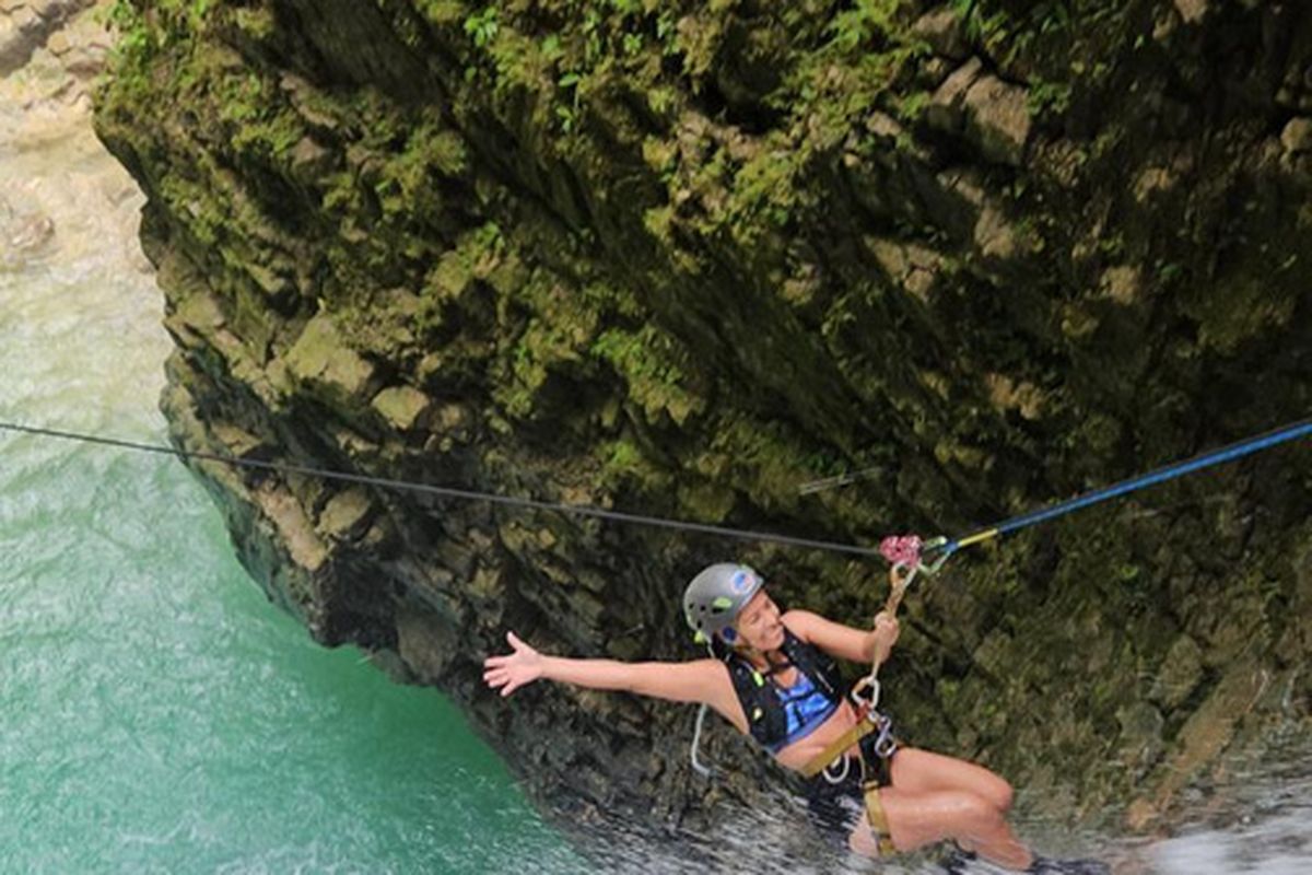 A canyoning guest sliding down a natural rock waterslide near Golfito