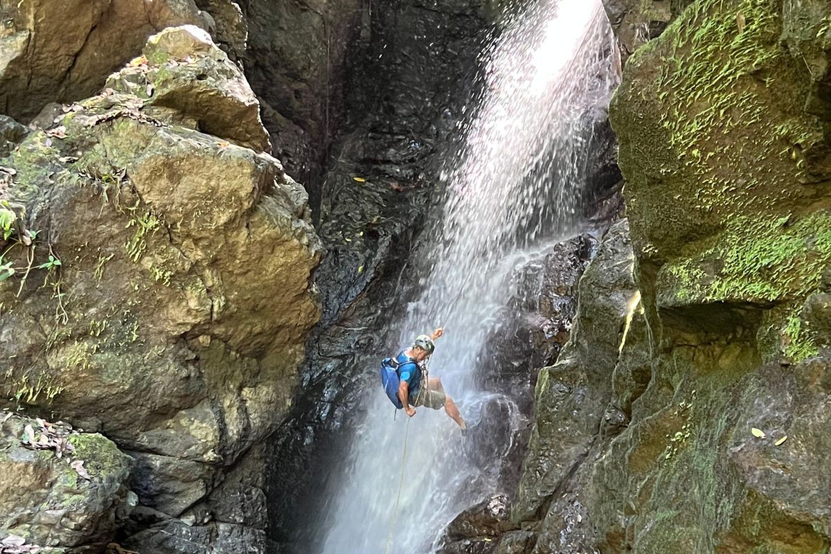 A person rappelling down a jungle waterfall on the Pavones canyoning tour