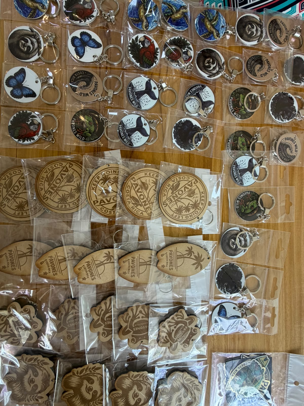 Pavones Wild keychains and laser-cut wooden surfboard souvenirs laid out on a wooden counter