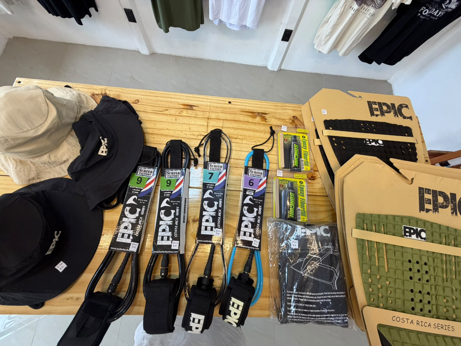Surfer Factory surfboard leashes, EPIC traction pads, Suncure ding repair kits and bucket hats on the hardware table at Pavones Surf Club